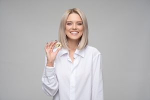 Image of a woman holding a bitcoin in her right hand.