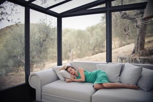 A woman is sleeping in a seat in the porch.